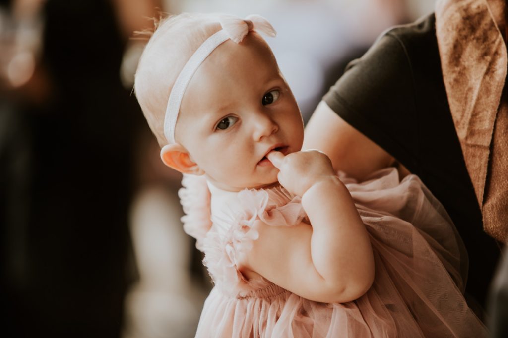 a baby with its finger in its mouth at a canal 337 wedding