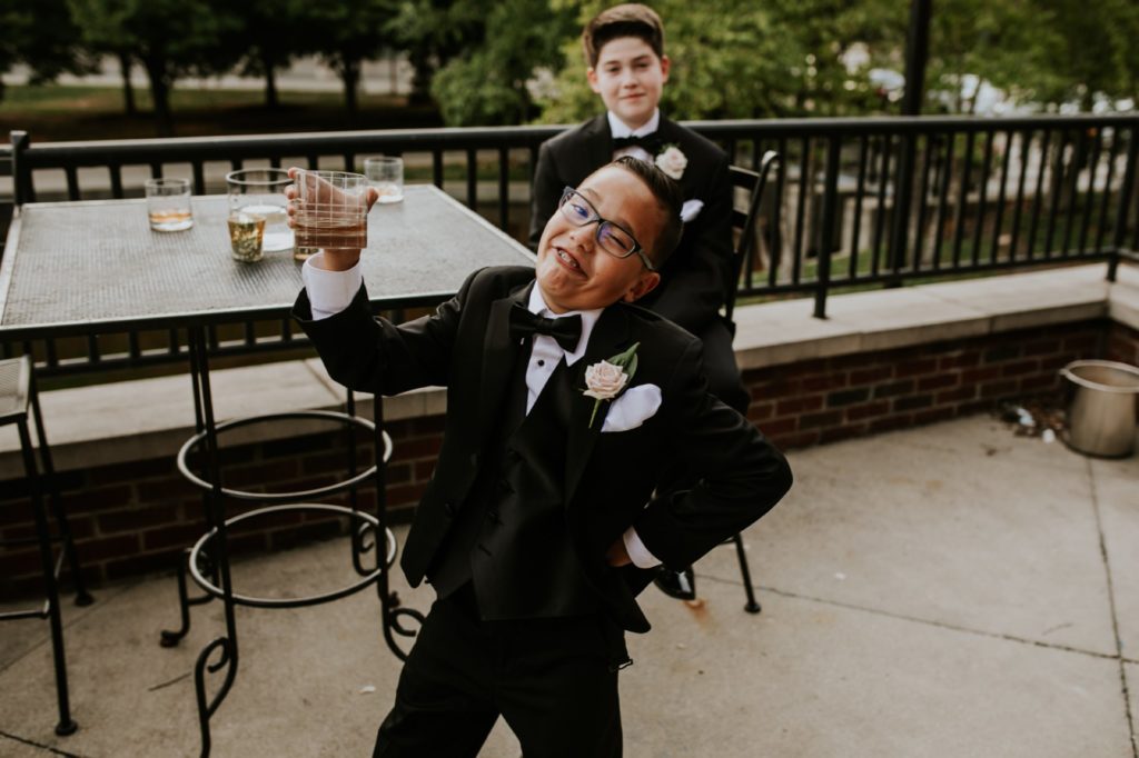 a young boy poses with a drink at a canal 337 wedding