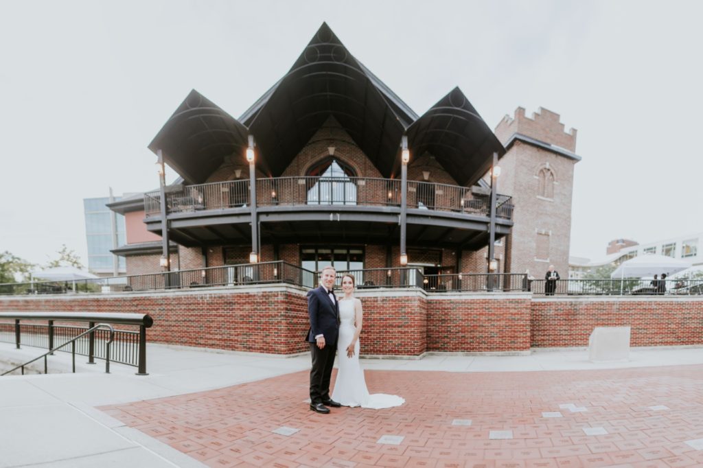 bride and groom stand in front of canal 337 building in a panoramic photo of the building