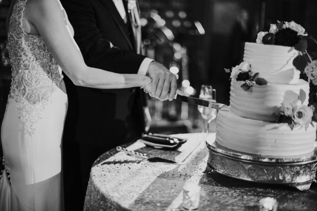 black and white photo of bride and groom cutting cake at an industrial wedding in indianapolis