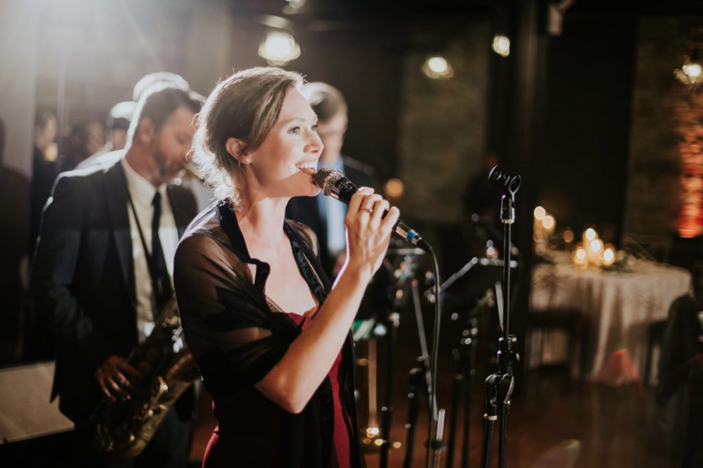 bridesmaid sings into microphone during wedding reception at a canal 337 wedding