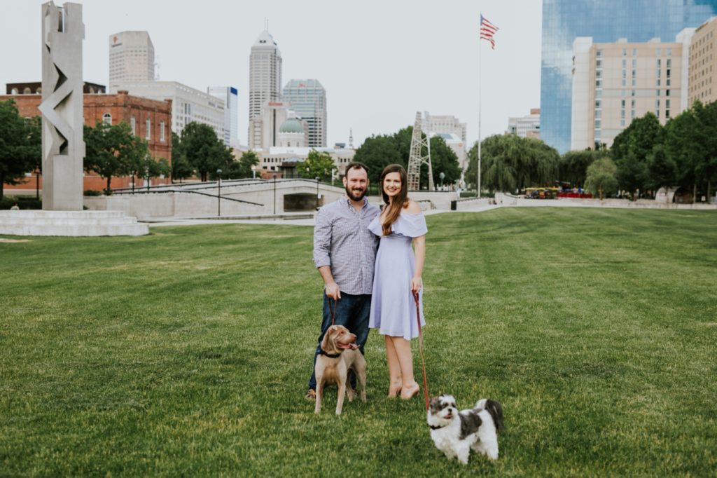 girl in blue dress iwth man in button down shirt with dogs for white river state park engagement picture