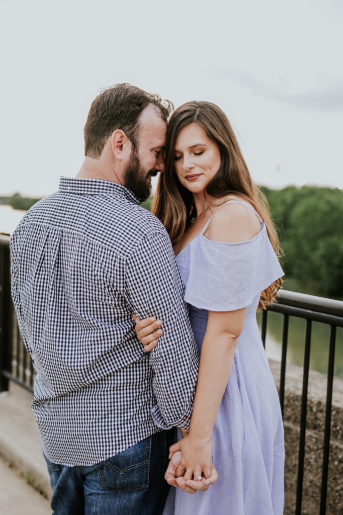 man in plaid shirt rest forehead against woman in blue dress in white river state park engagement picture