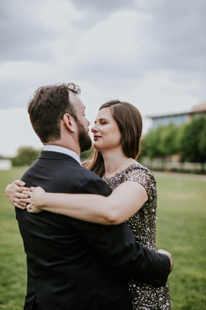 woman in ball gown kisses man in suit on grass in downtown Indianapolis park