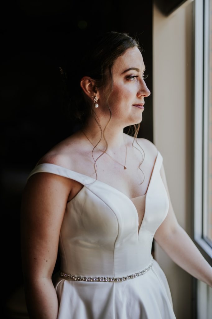 bride looks out window of church before wedding