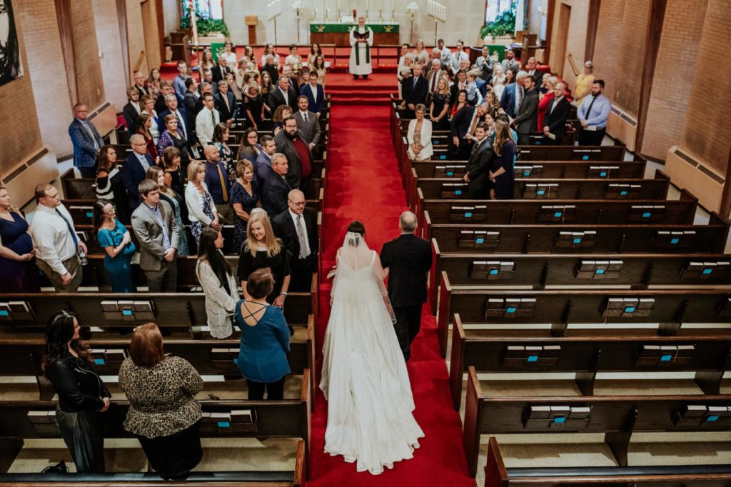 bride walks down aisle of church in kokomo with red carpet