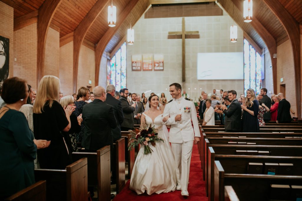 bride and groom walk away from front of church after wedding
