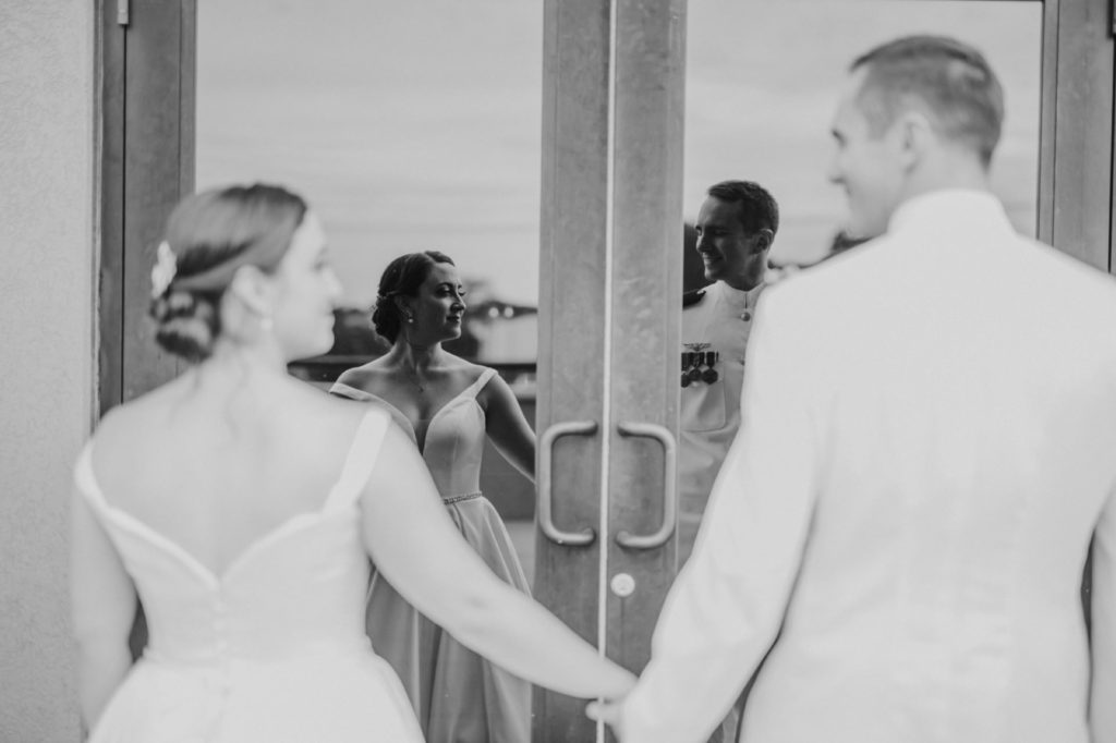 black and white photo of bride and groom holding hands  and their reflection in doors of Bel Air Kokomo Wedding