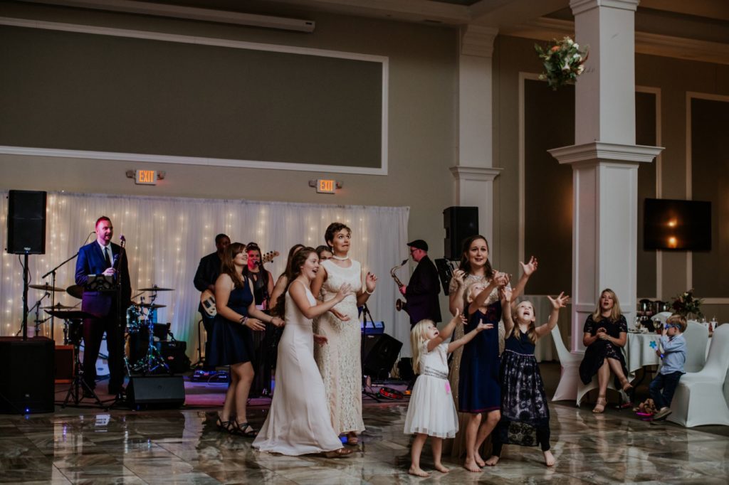 girls jump to grab bouquet at a Bel Air Kokomo Wedding