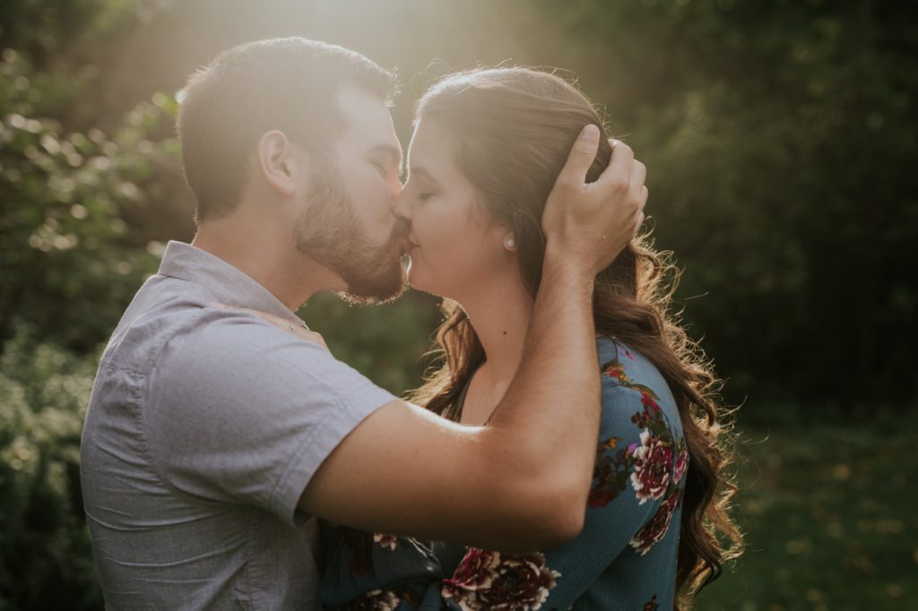 a man and a woman kiss in the light of a setting sun at their IMA engagement session
