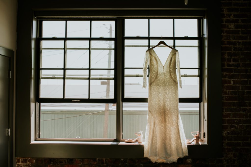 wedding dress hangs in industrial windows of blumlux building
