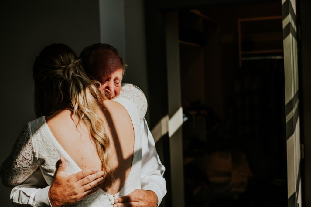 father of the bride hugs his daughter and cries during father daughter reveal at blumlux building in indy