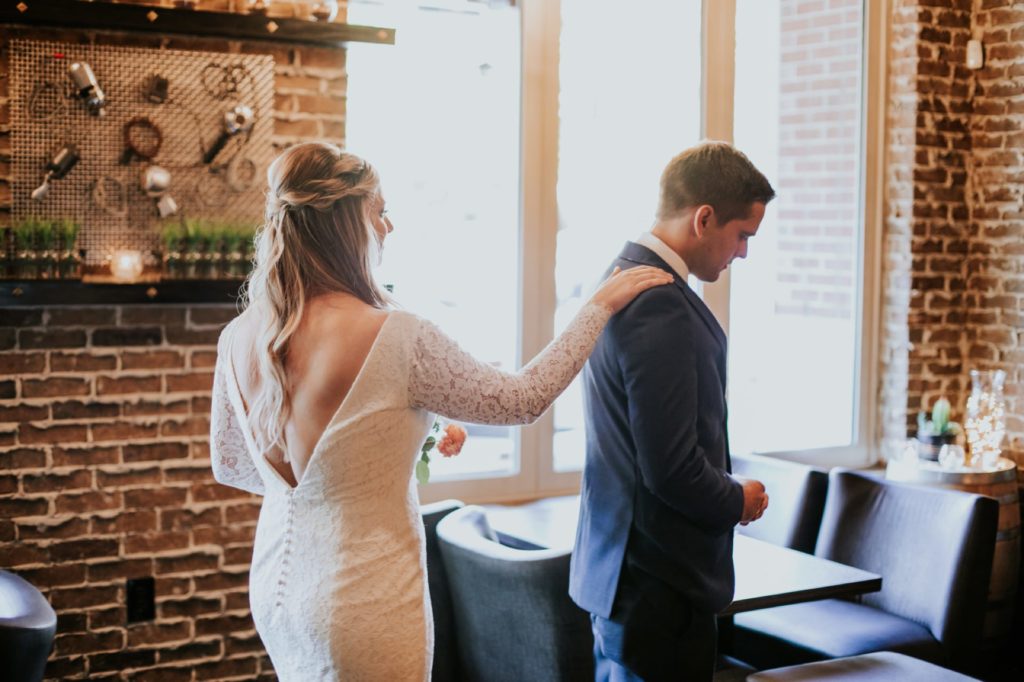 bride taps groom on shoulder during first look in the ball and biscuit