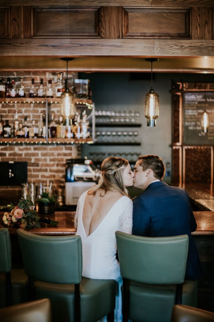 bride and groom kiss at the bar at the ball and biscuit in downtown indianapolis