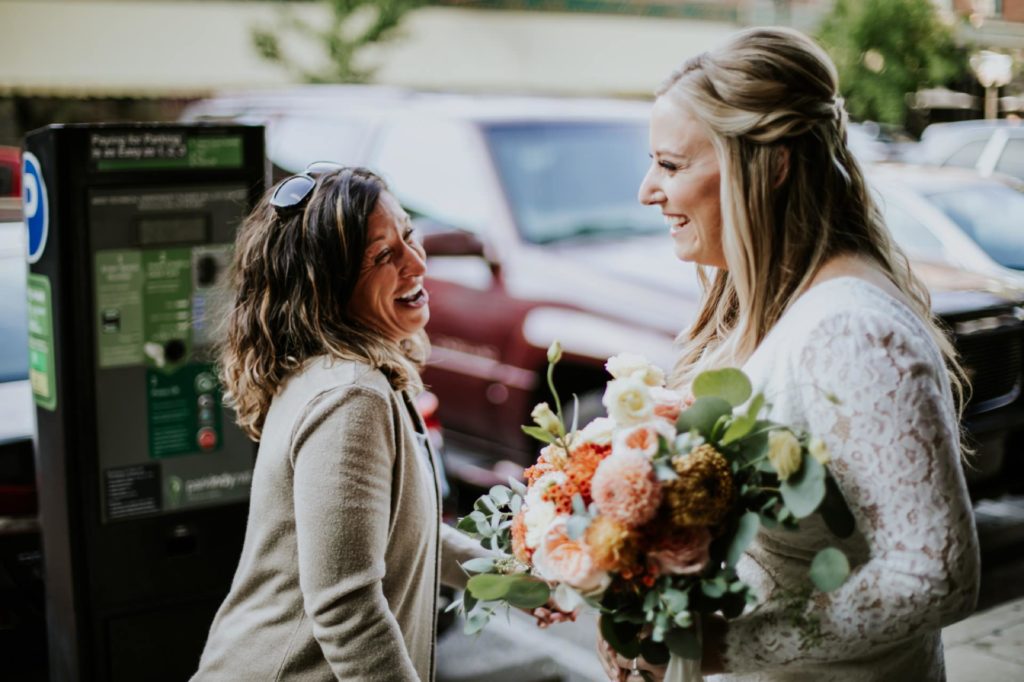 woman laughs and talks to bride outside the ball and biscuit