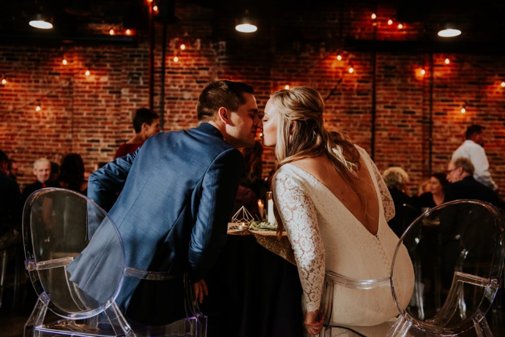 bride and groom kiss at sweetheart table at a VisionLoft Wedding