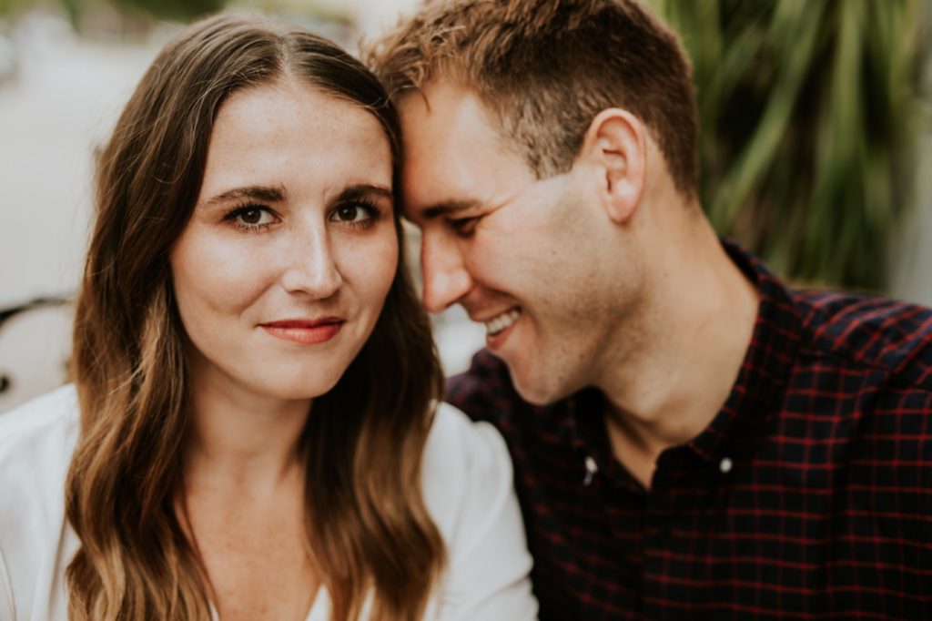 smiling man touches his forehead to a woman's head during their Louies Wine Dive engagement portraits
