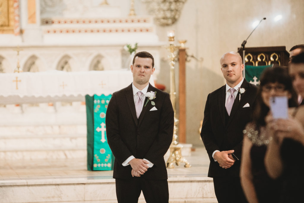 groom tearing up in Saint John the Evangelist Catholic Church as he sees the bride for the first time on the wedding day
