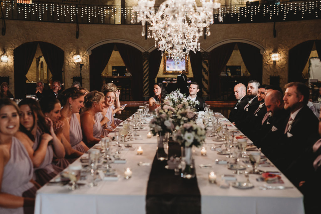 wedding party seated at head table with hang chandeliers at an Indiana Roof Ballroom wedding