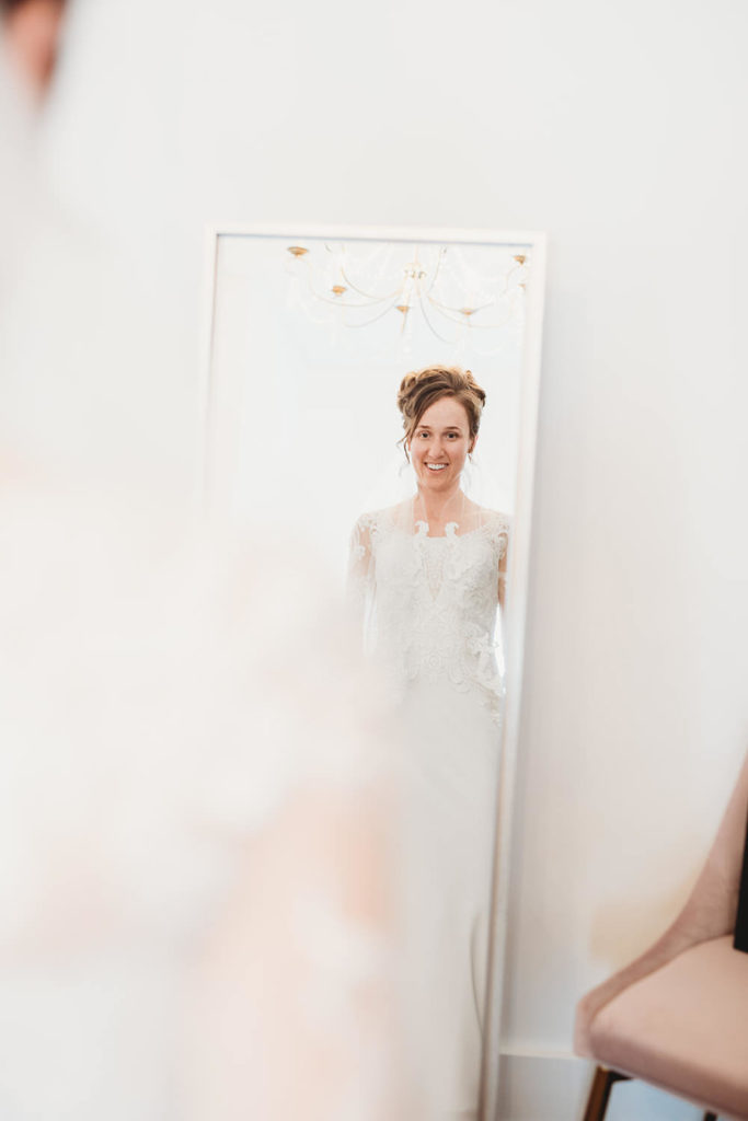 bride sees herself in mirror after putting on wedding dress at a carmel wedding