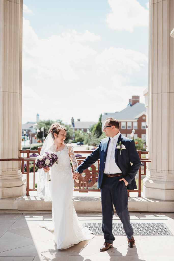 bride and groom hold hands and walk in shade at the palladium in Carmel Indiana