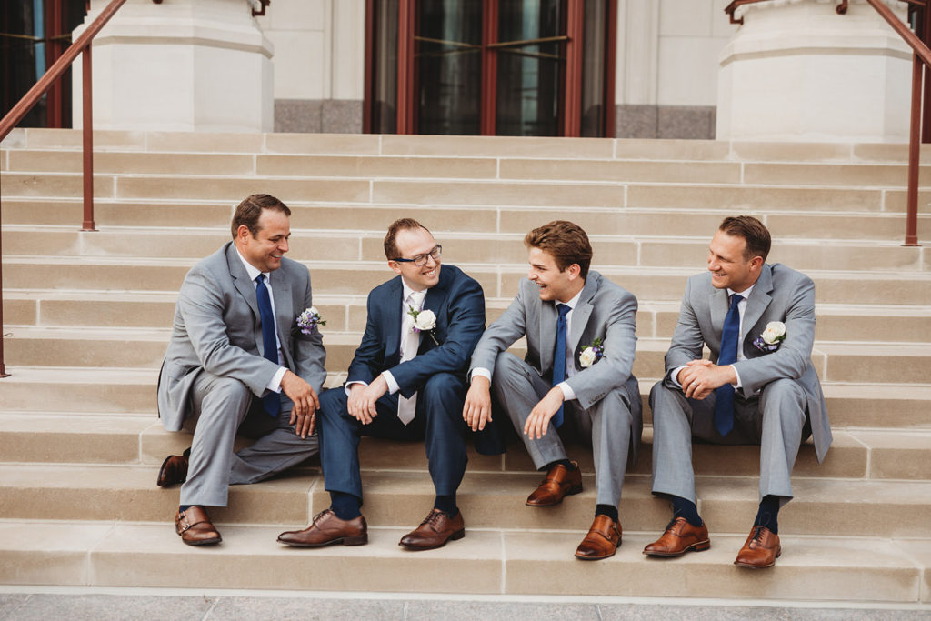 groom sits on steps with groomsmen