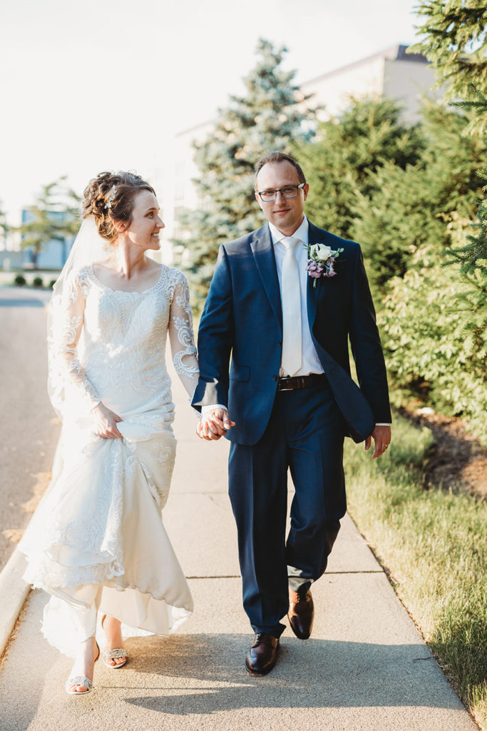 bride and groom hold hands and walk down the street
