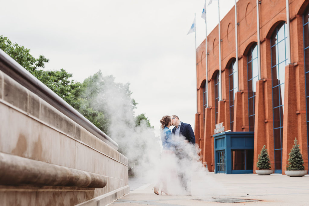 man and woman kiss in steam during white river park engagement session