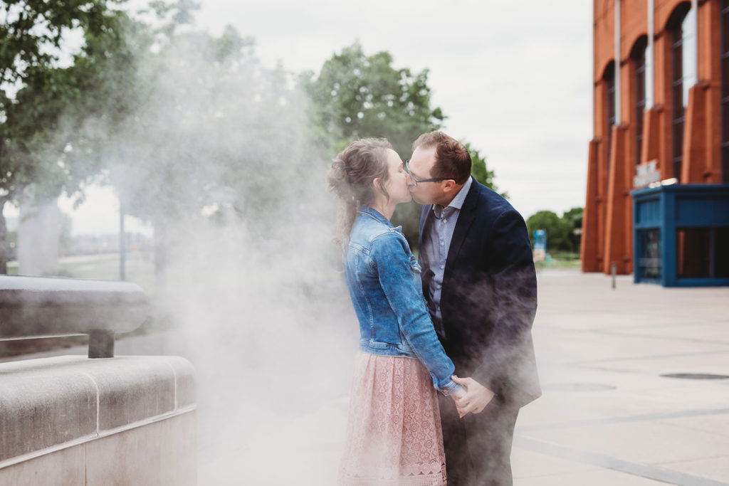 man and woman kiss passionately in steam during white river park engagement session