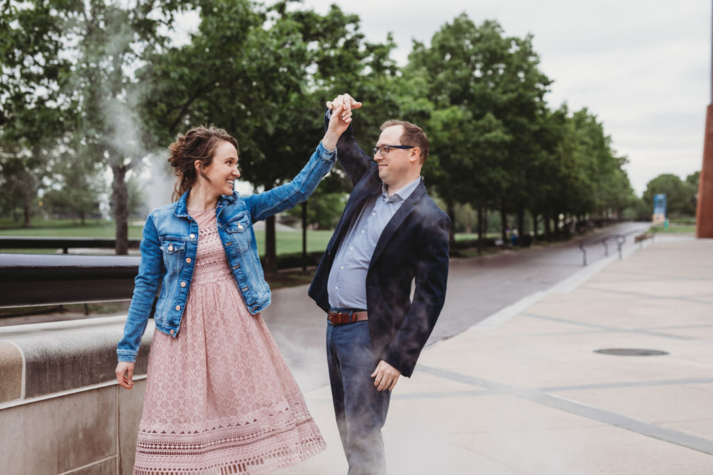 man and woman dance in steam during downtown indianapolis engagement session