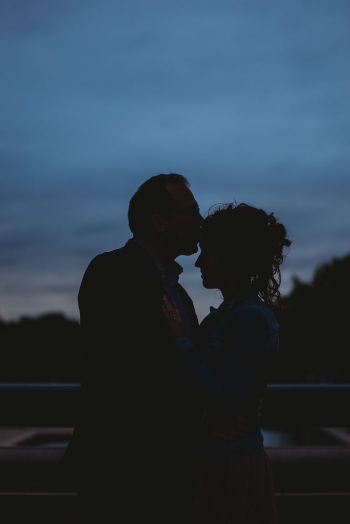 silhouette of man kissing woman on forehead during white river park engagement session