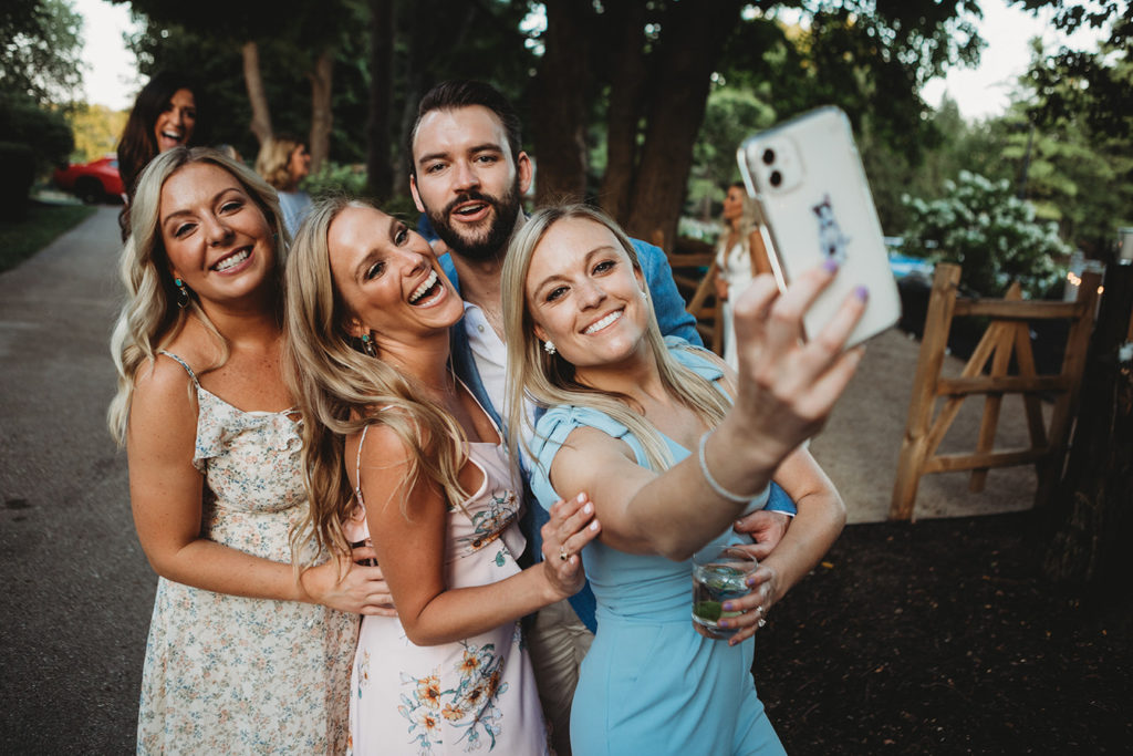 girls and boy take selfie during wedding reception in carmel