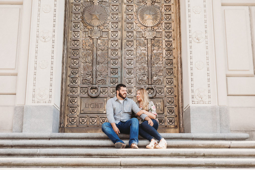 blonde woman and man with beard in front of gold doors of indiana war memorial