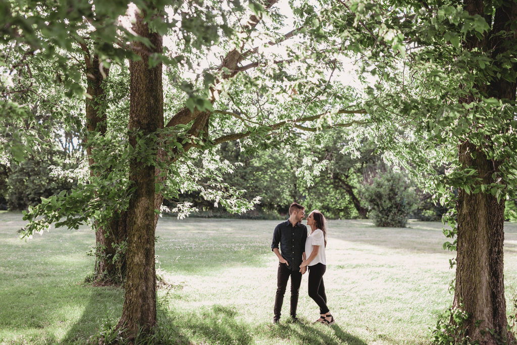 man and woman hug under two trees during their noblesville engagement session