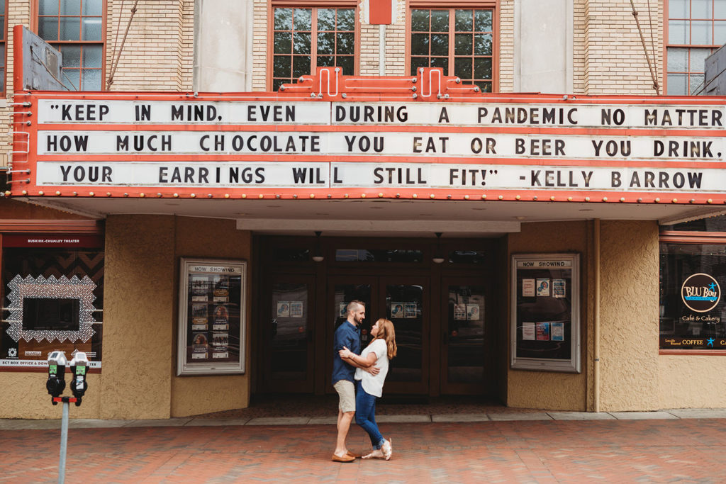 couple hugs under marquee of Buskirk-Chumley Theater during their bloomington engagement session