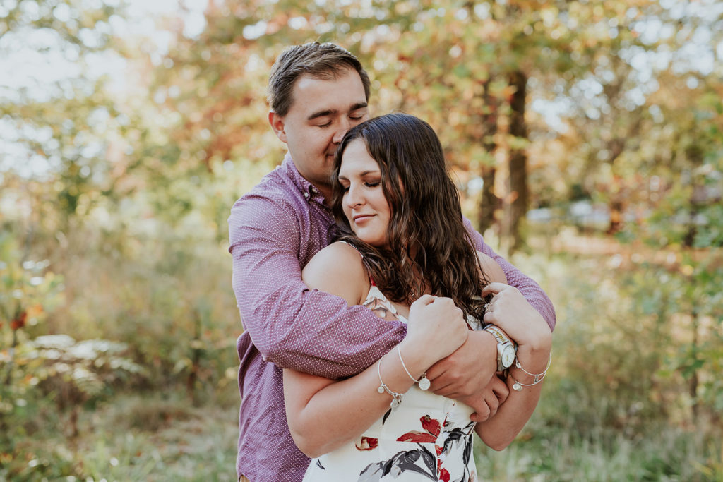 man hugs woman from behind at coxhall gardens engagement session