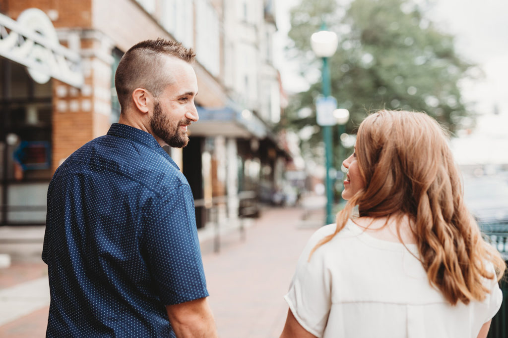 couple hold hands and look at each other during their bloomington engagement session