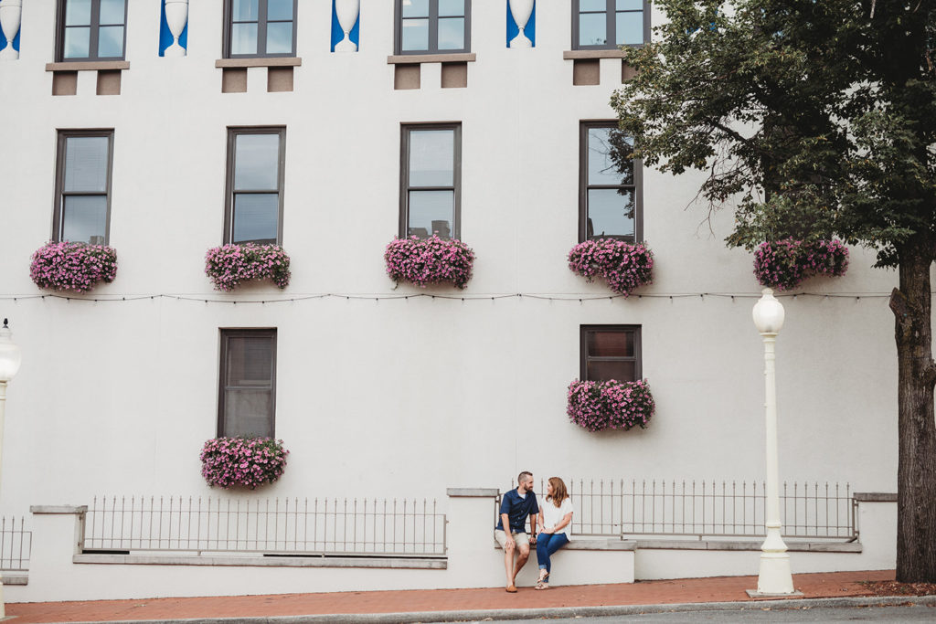 couple sit on wall during their bloomington engagement session
