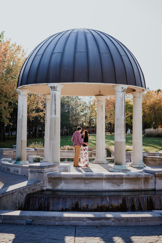 man and woman dance under gazebo at coxhall gardens engagement session