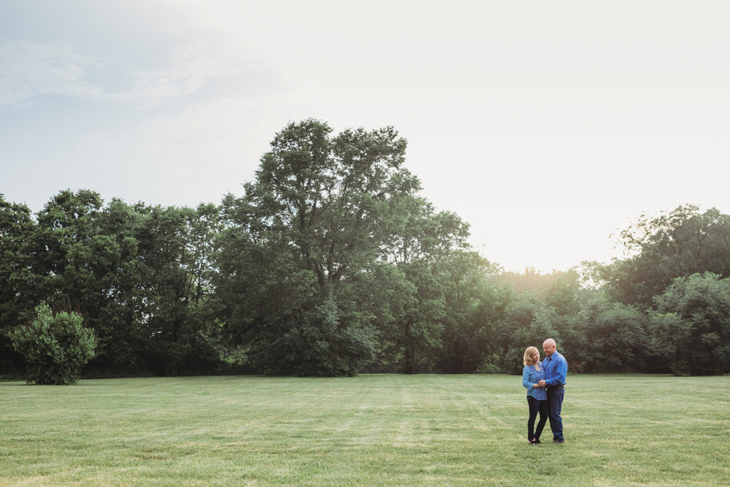 man and woman in field at sunset during their hamilton county park engagement session