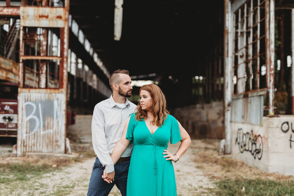 man and woman look past each other while holding hands at one world at woolery mill during their bloomington engagement session
