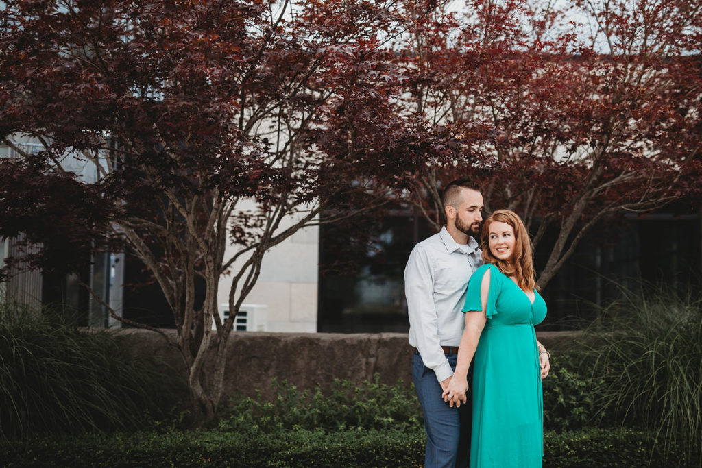 couple holds hands in front of japanese maple trees at one world at woolery mill during their bloomington engagement session