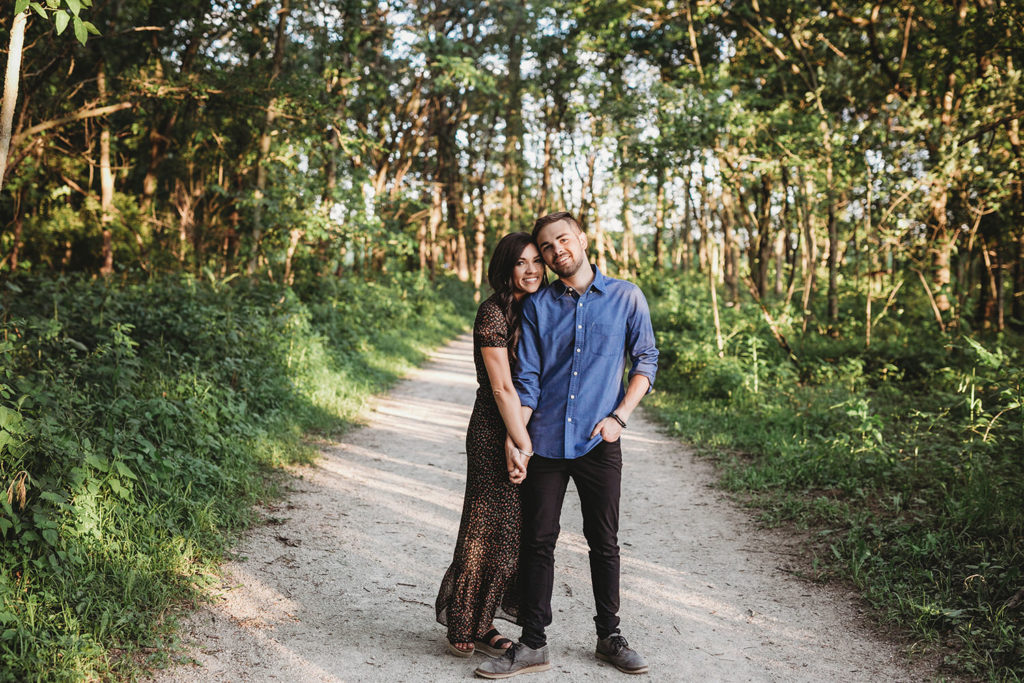 wide shot of couple standing on path in woods during their Strawtown Koteewi Park engagement session