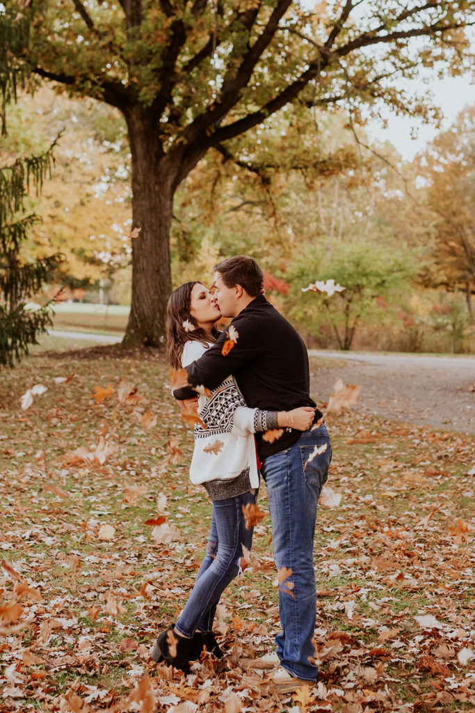 leaves fall around man and woman kissing at their coxhall gardens engagement session