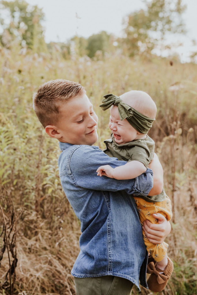 boy in denim shirt holds baby sister as she cries in Indy family photos