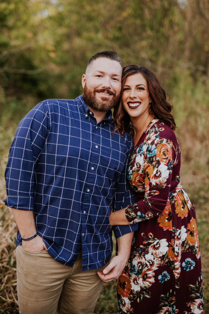 man in flannel and woman in floral print dress hug and smile