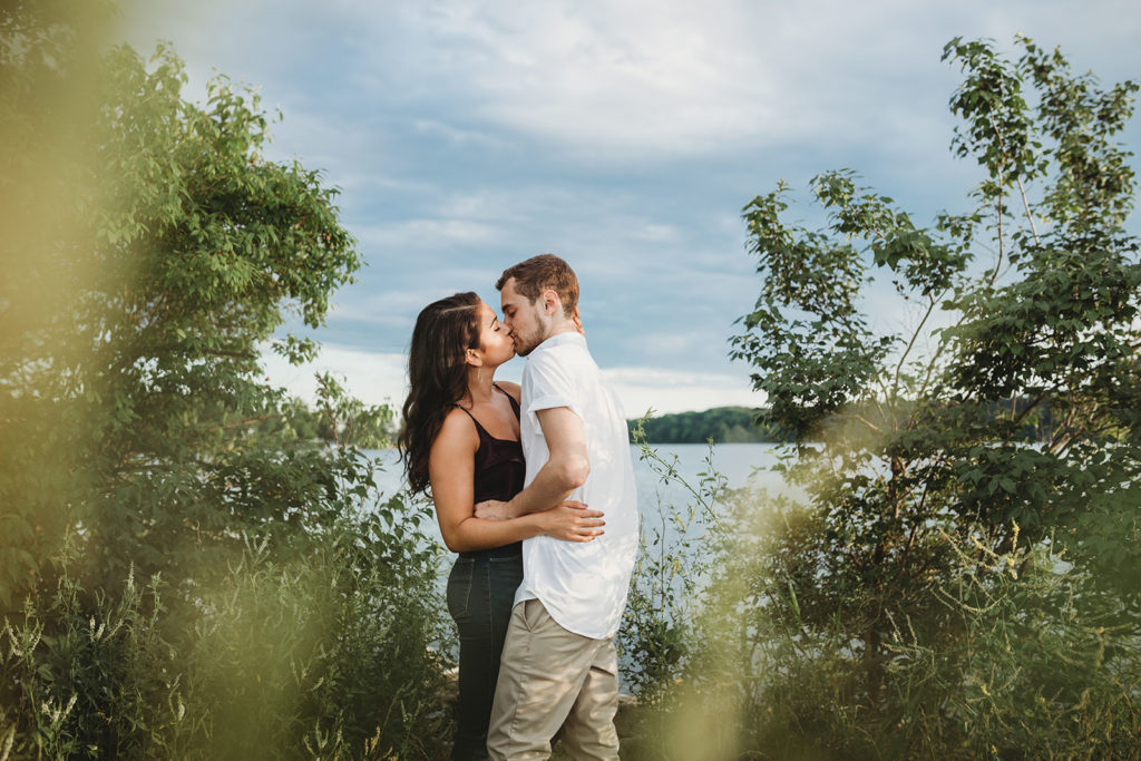 young man and young woman kiss in front of Eagle Creek Reservoir