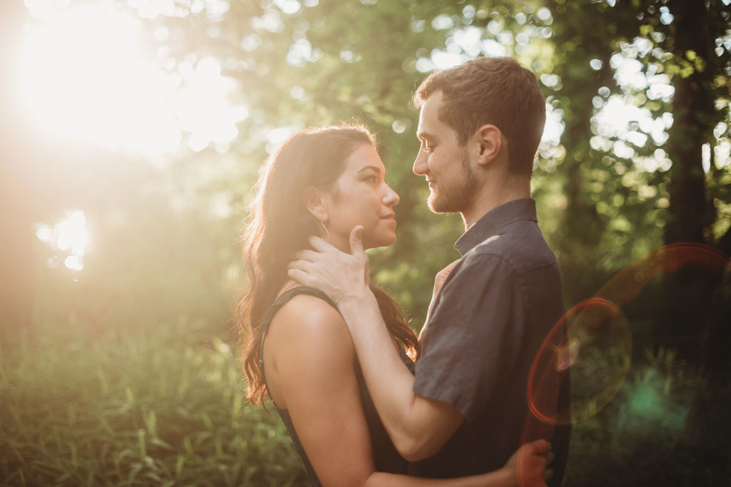 young man and woman hug in front of sunset at Eagle Creek Reservoir Engagement