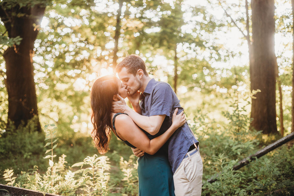 young couple passionately kissing while two suns set behind them during their Eagle Creek Reservoir Engagement