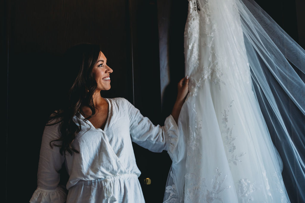 gorgeous bride holding wedding dress and looking at it lovingly before her carmel backyard wedding